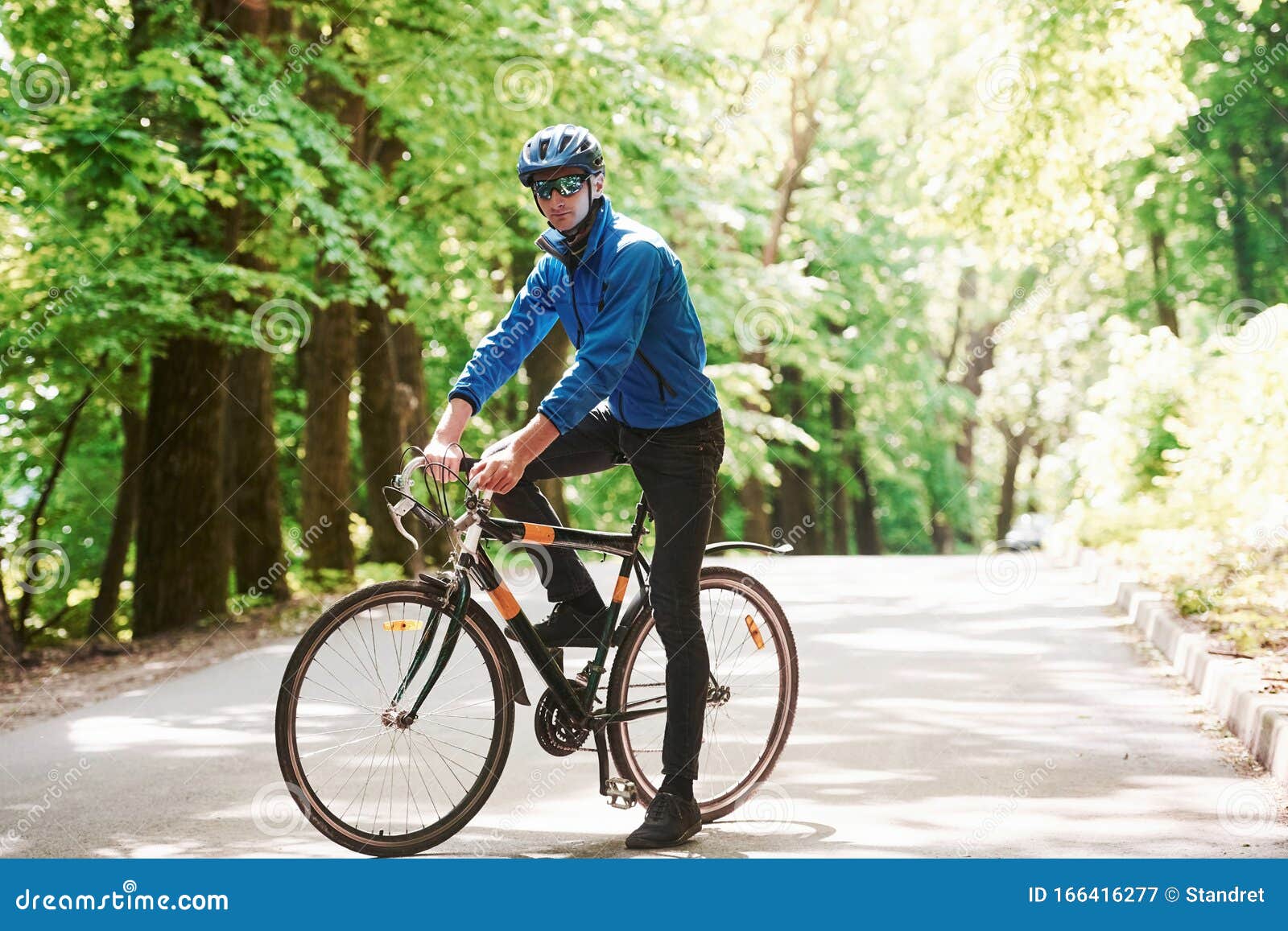 Posando Para Una Cámara Ciclista En Bicicleta Está En La Carretera De  Asfalto En El Bosque En El Día Soleado Imagen de archivo - Imagen de casco,  afuera: 166416277