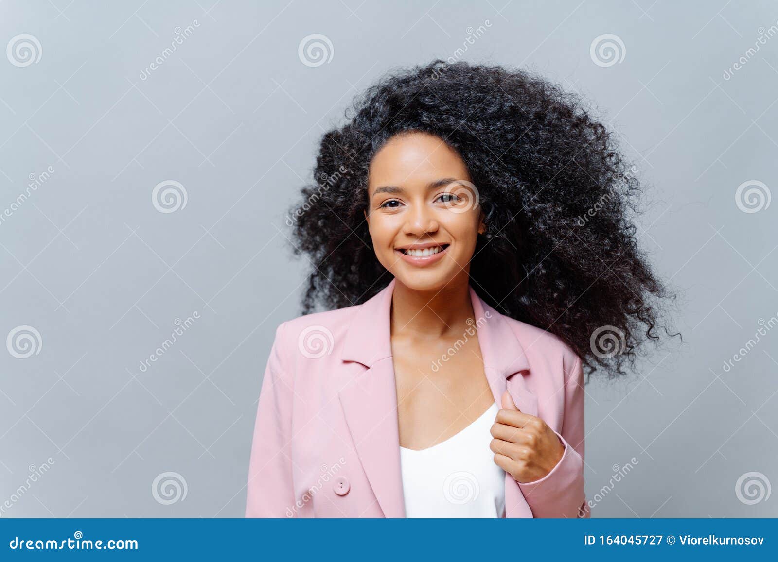 Positive Curly Dark Skinned Woman With Luminous Hair Wears Formal