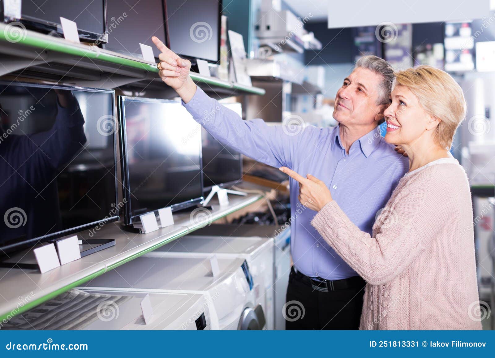 positive husband and wife choose for themselves tv in center of electronics
