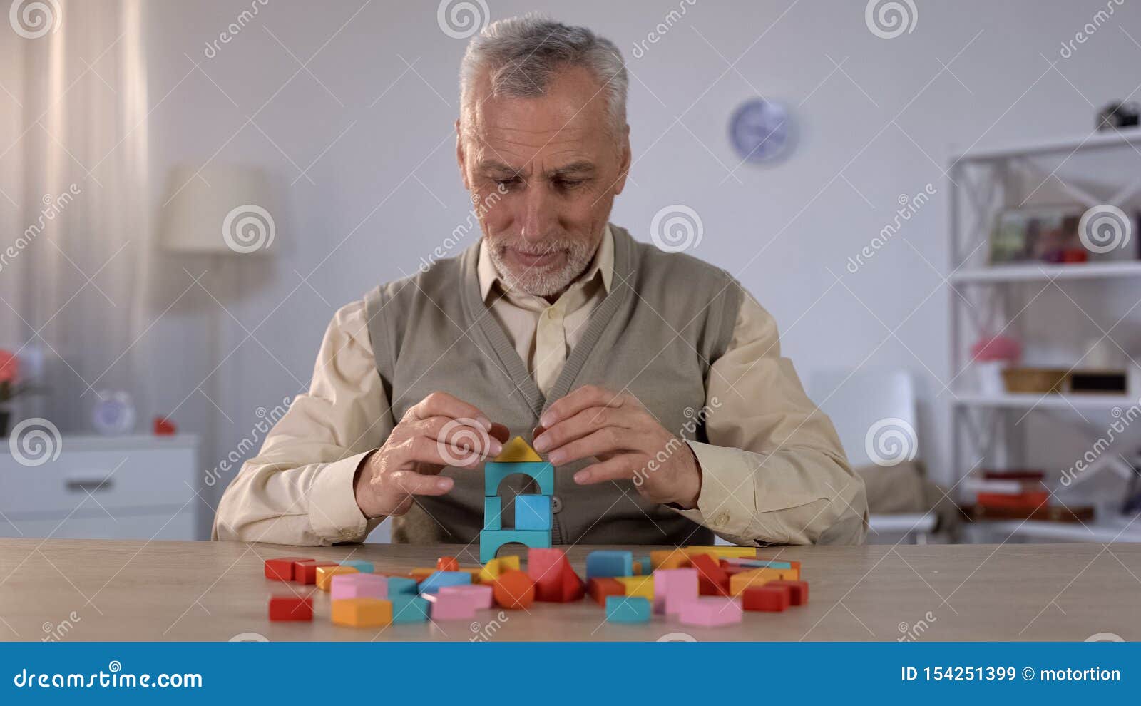 positive old man playing with wooden cubes, cognitive training in alzheimer