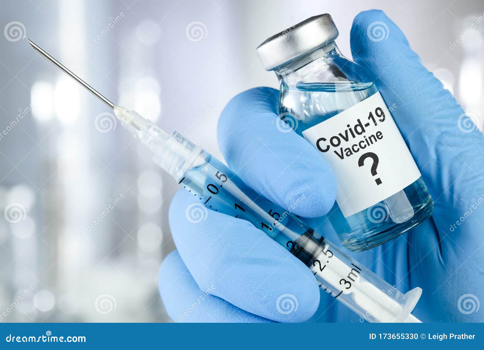 possible cure with a hand in blue medical gloves holding coronavirus, covid 19 virus, vaccine vial