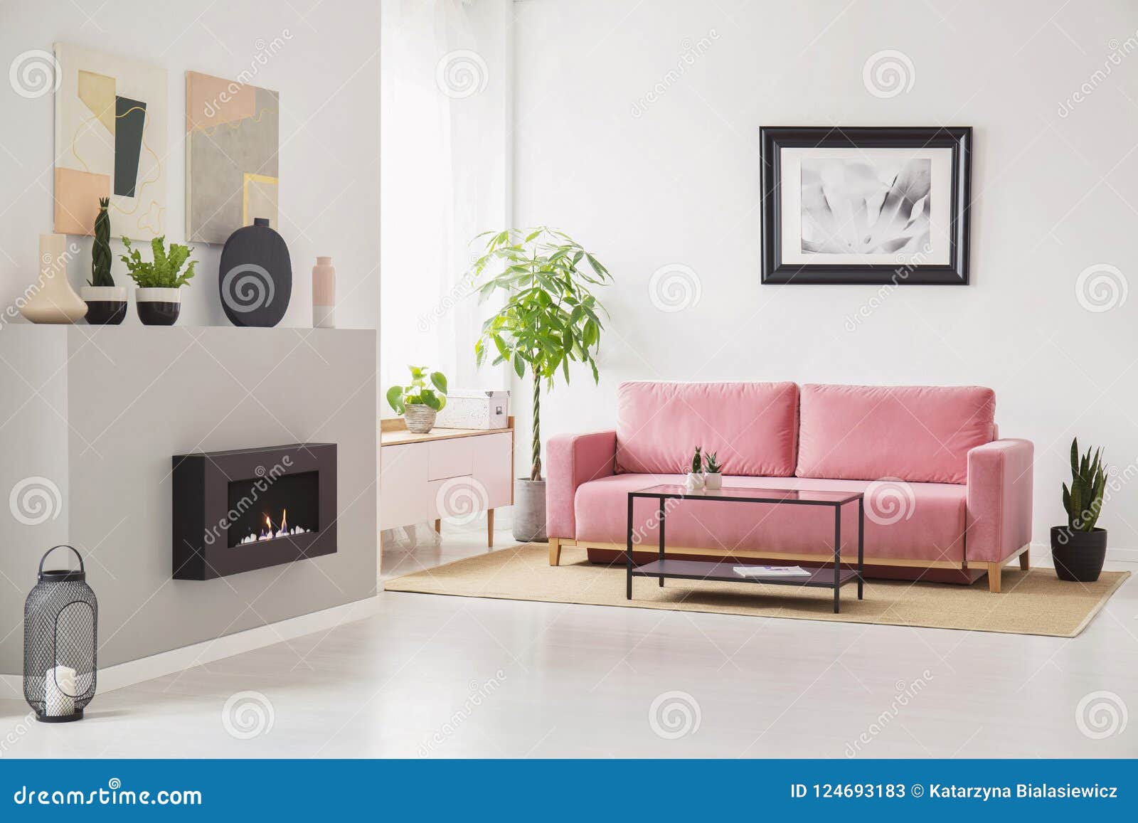 posters on walls in scandi sitting room interior with pink velvet couch, fresh plants, fireplace and decor