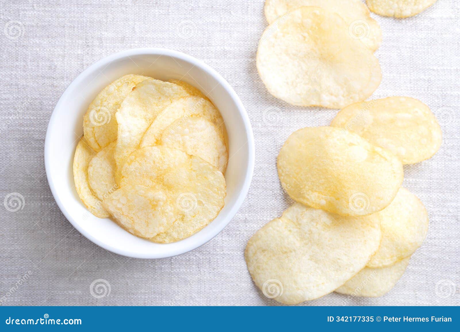 salted potato chips, crisps, fried potato slices in a white bowl on linen