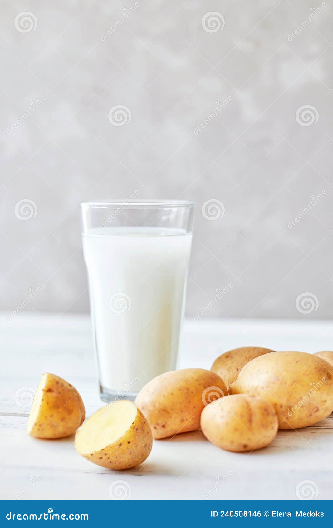 potato milk in a glass mug stands on the table next to fresh potato tubers. alternative plant based milk. food trends