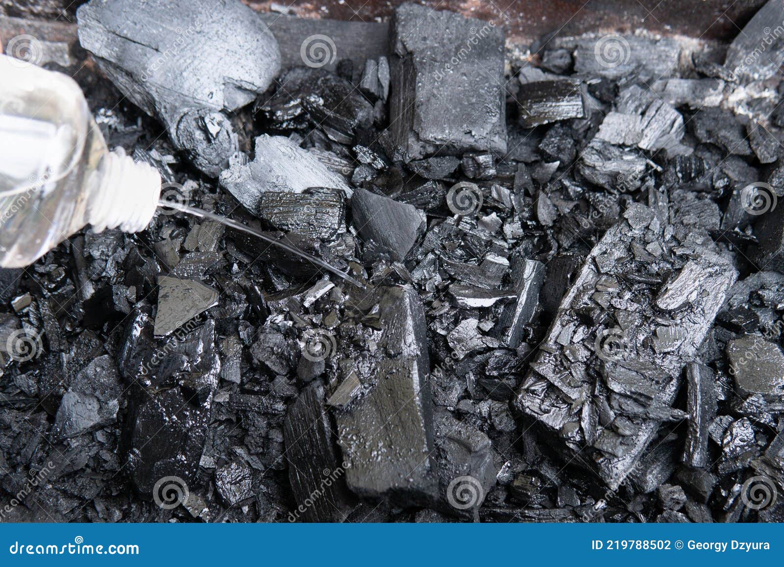 Pouring Charcoal Ignition Fluid before Lighting the Barbecue Charcoal