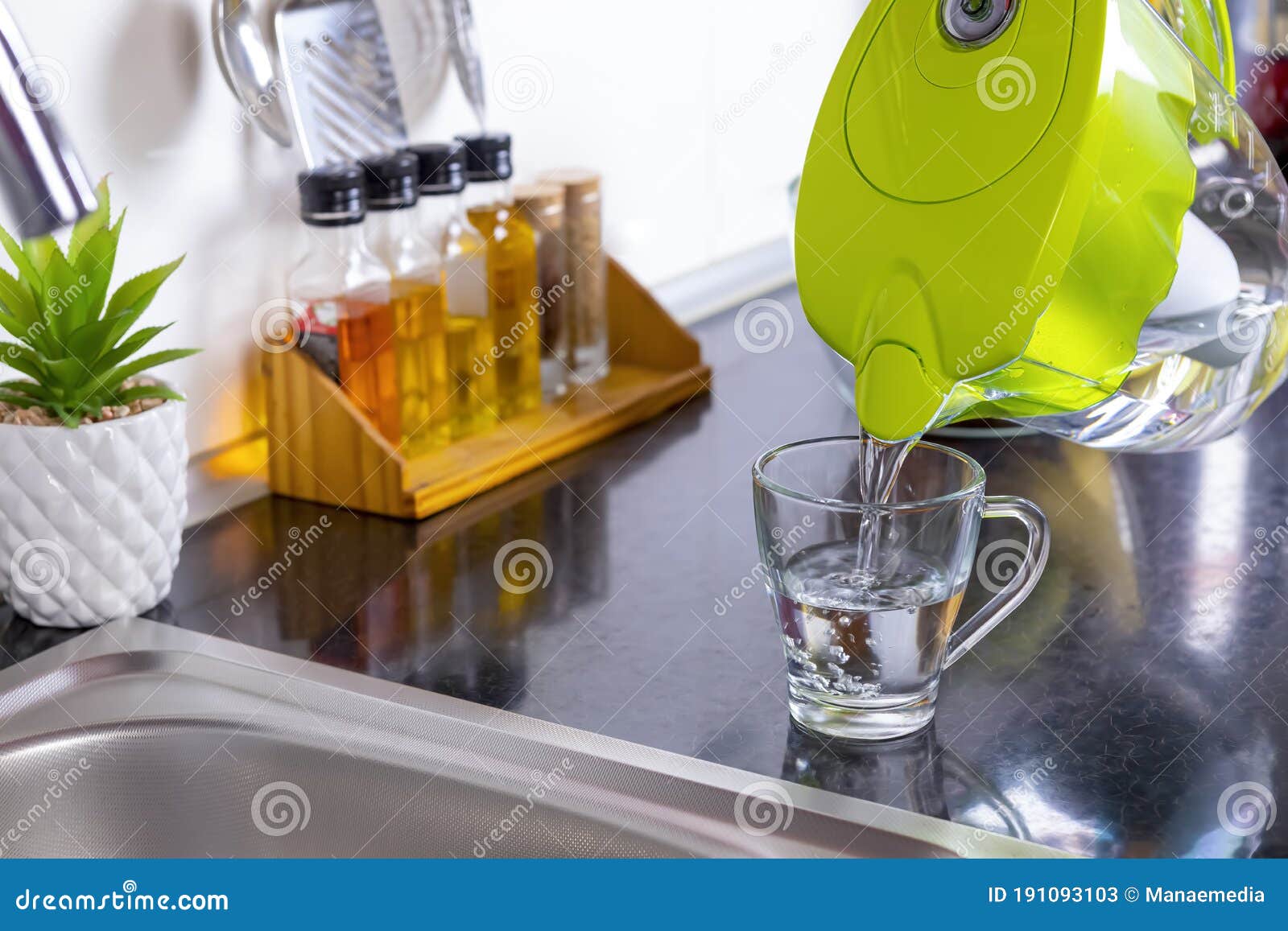 pouring filtered water into glass from jug in the kitchen