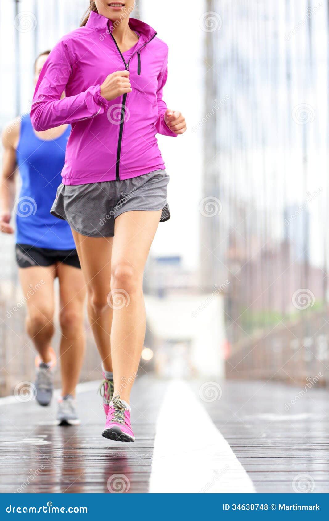 Povos running - pares que movimentam-se em New York City. Povos running - acople movimentar-se e treinar para a maratona. Corredores na chuva fora. As mulheres asiáticas e o corredor caucasiano e a aptidão dos homens ostentam os modelos que movimentam-se na ponte de Brooklyn, New York City, EUA.