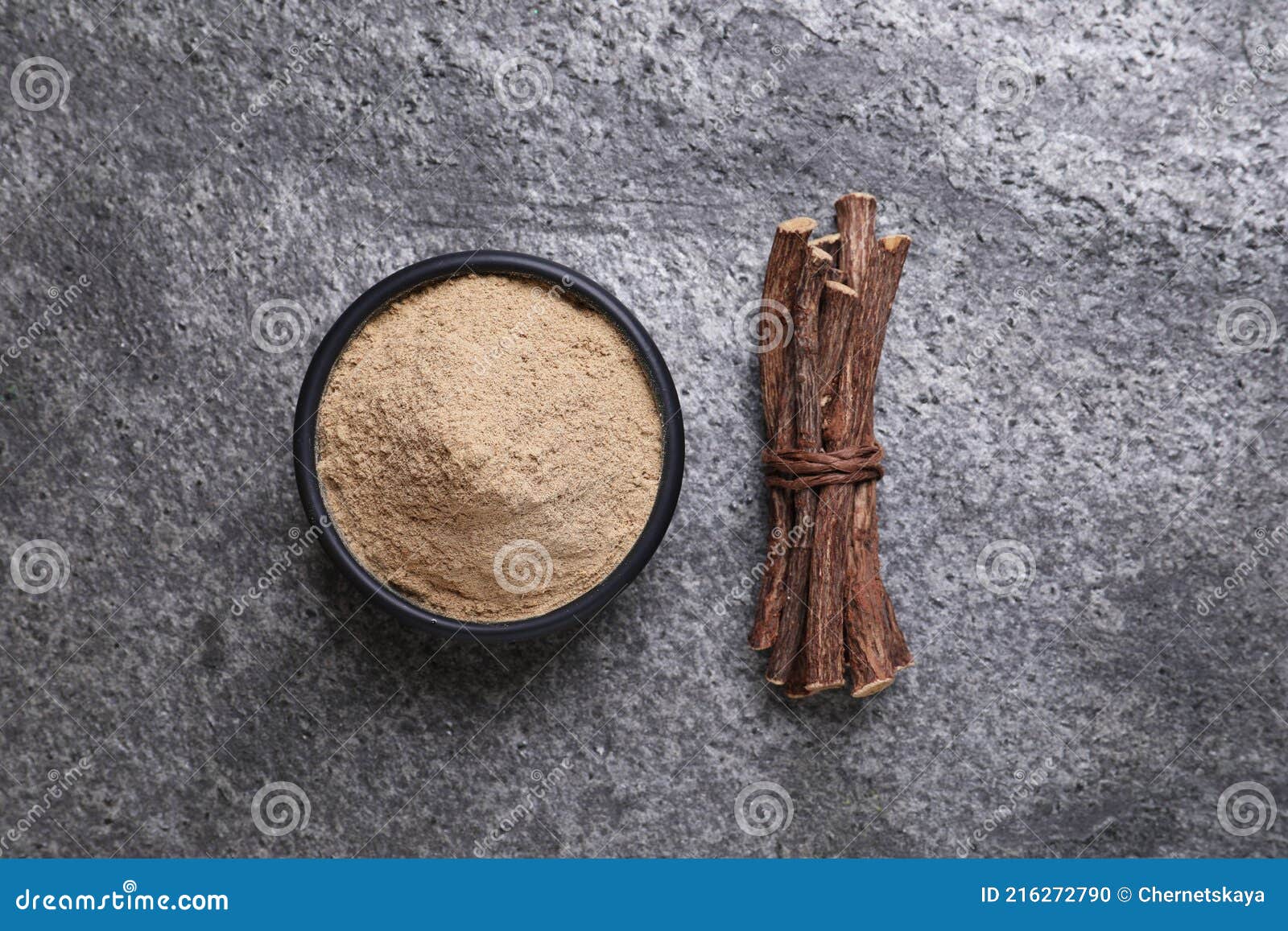 Powder in Bowl and Dried Sticks of Liquorice Root on Grey Table, Flat