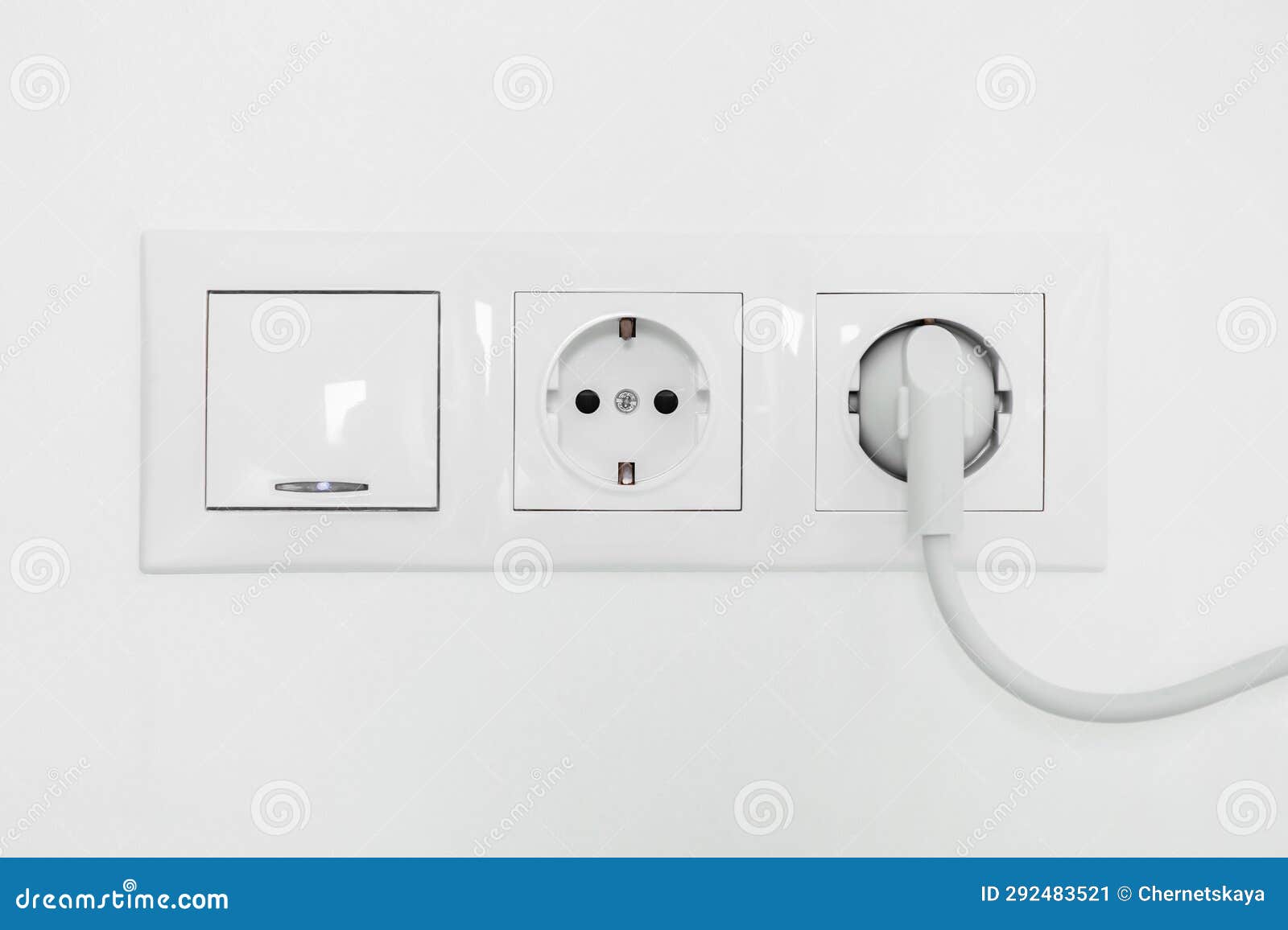 Power Sockets with Inserted Plug and Light Switch on White Wall Indoors