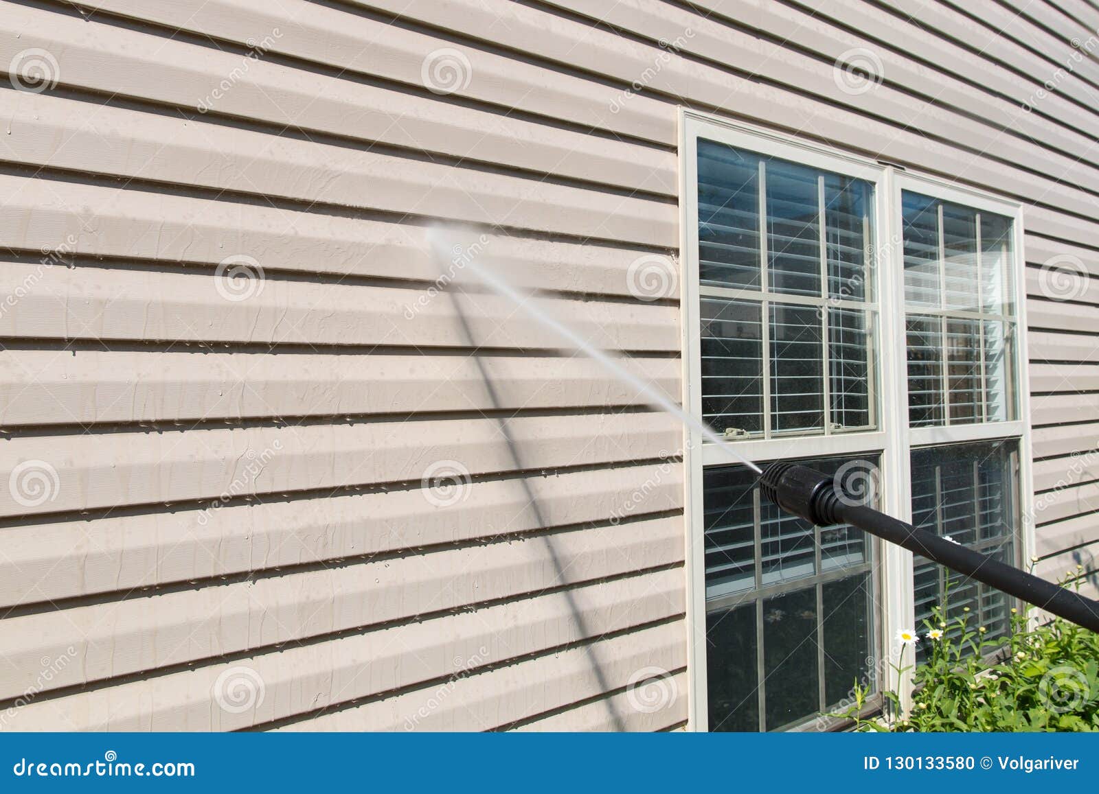 power washing. house wall siding cleaning with high pressure water jet.