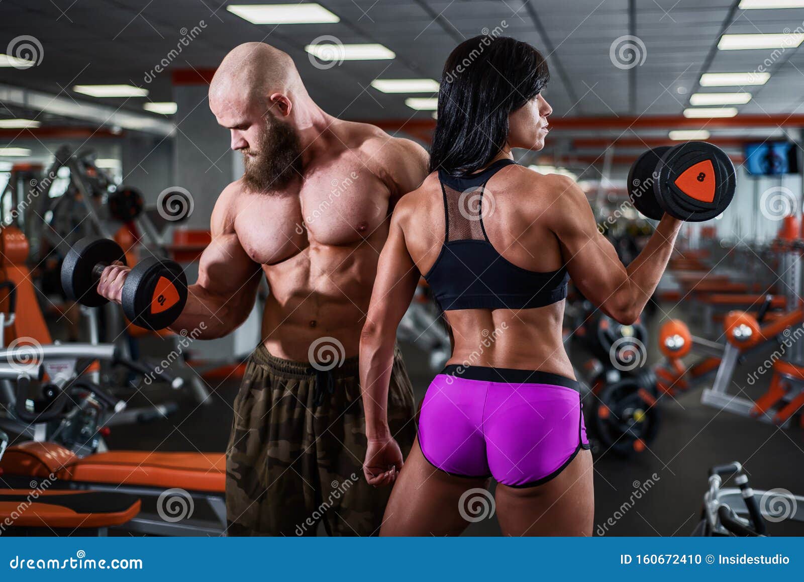 Powerful Muscular Strong Man And Woman Pick Up The Dumbbell With