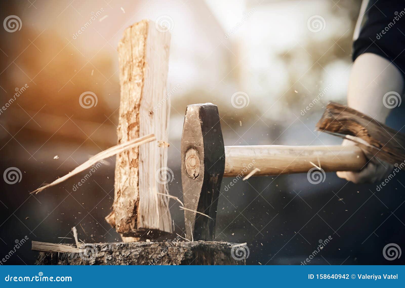 An Axe Cuts a Log into Pieces, from Which Splinters Fly Stock Photo