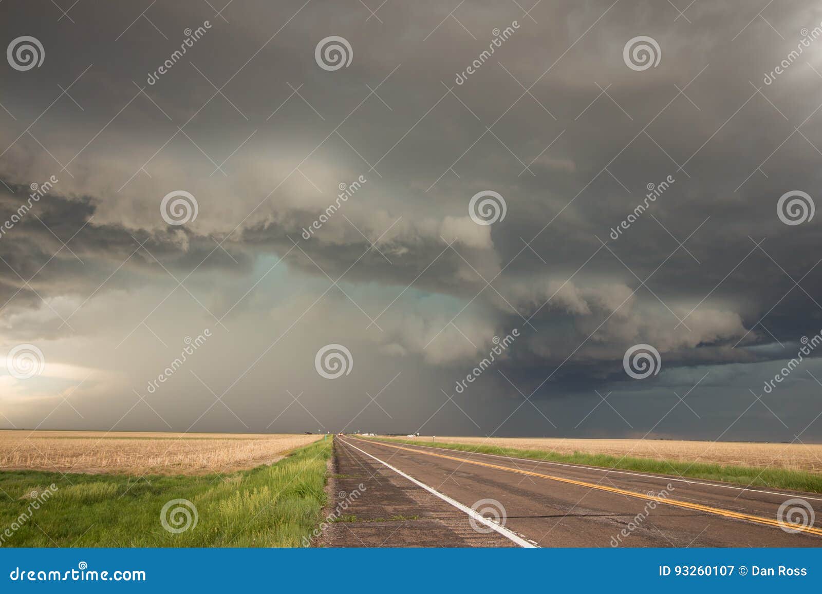 a powerful supercell thunderstorm looms over the highway.