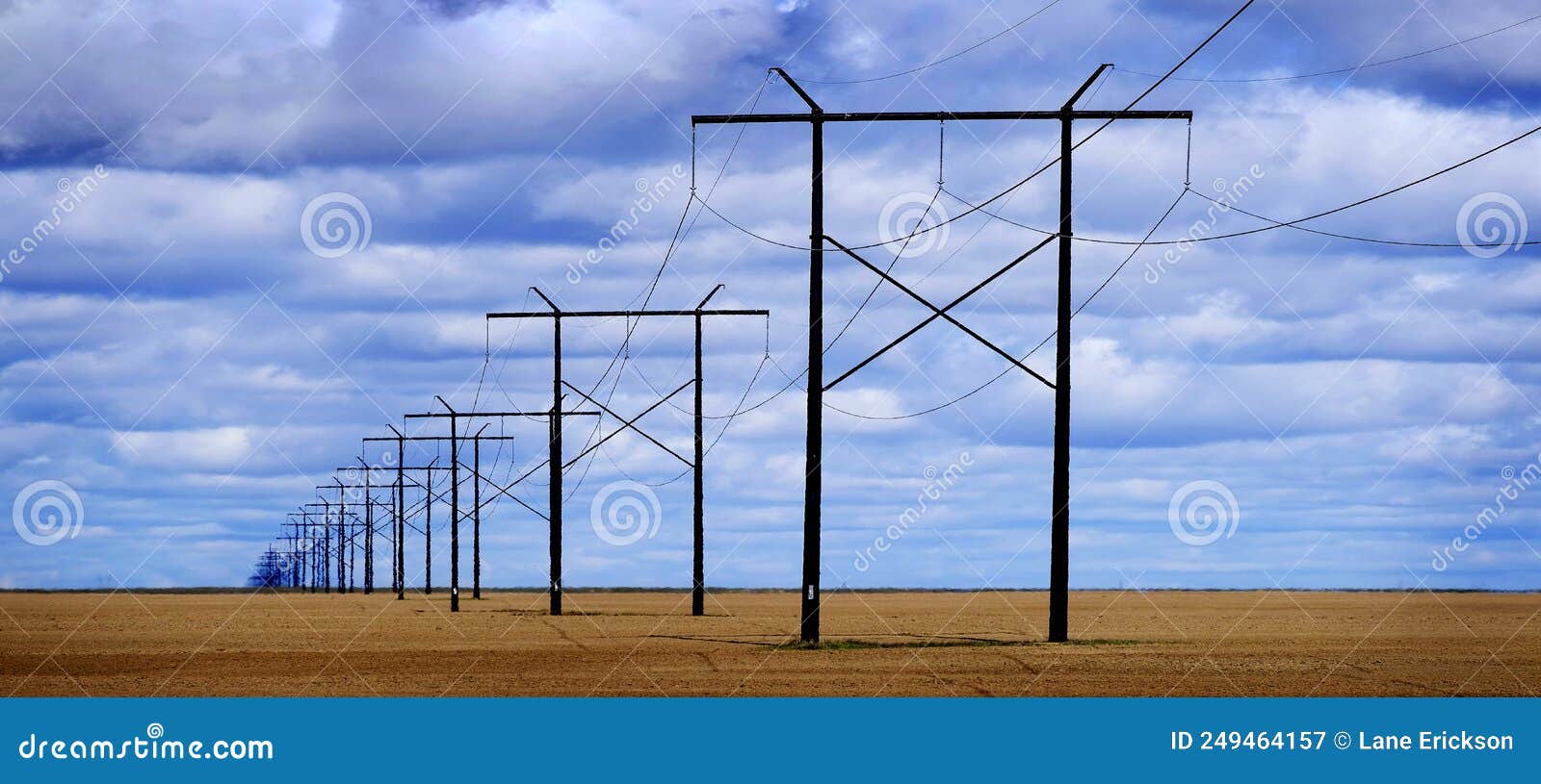 powerlines in field with blue sky and clouds