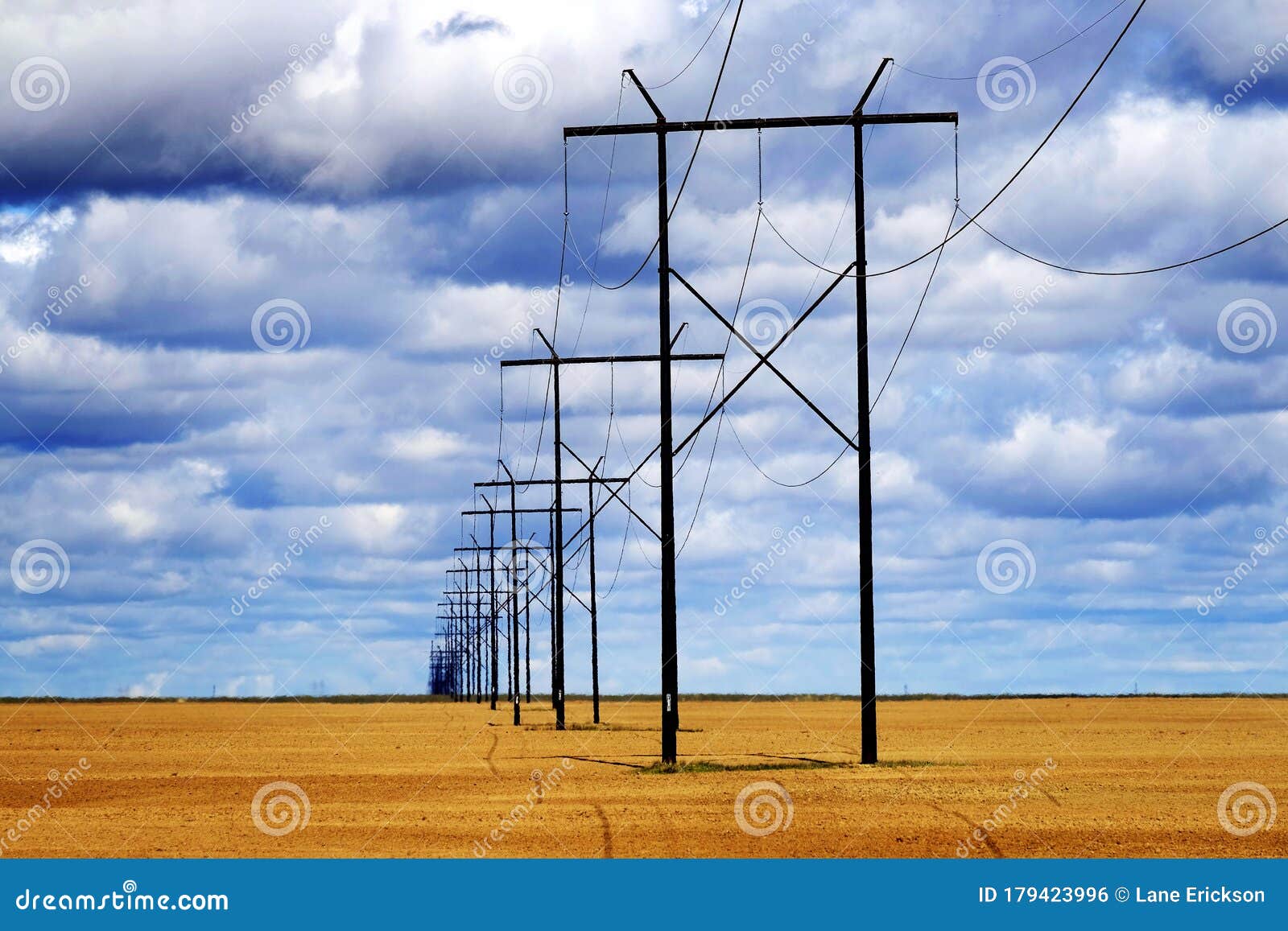 powerlines in field with blue sky and clouds