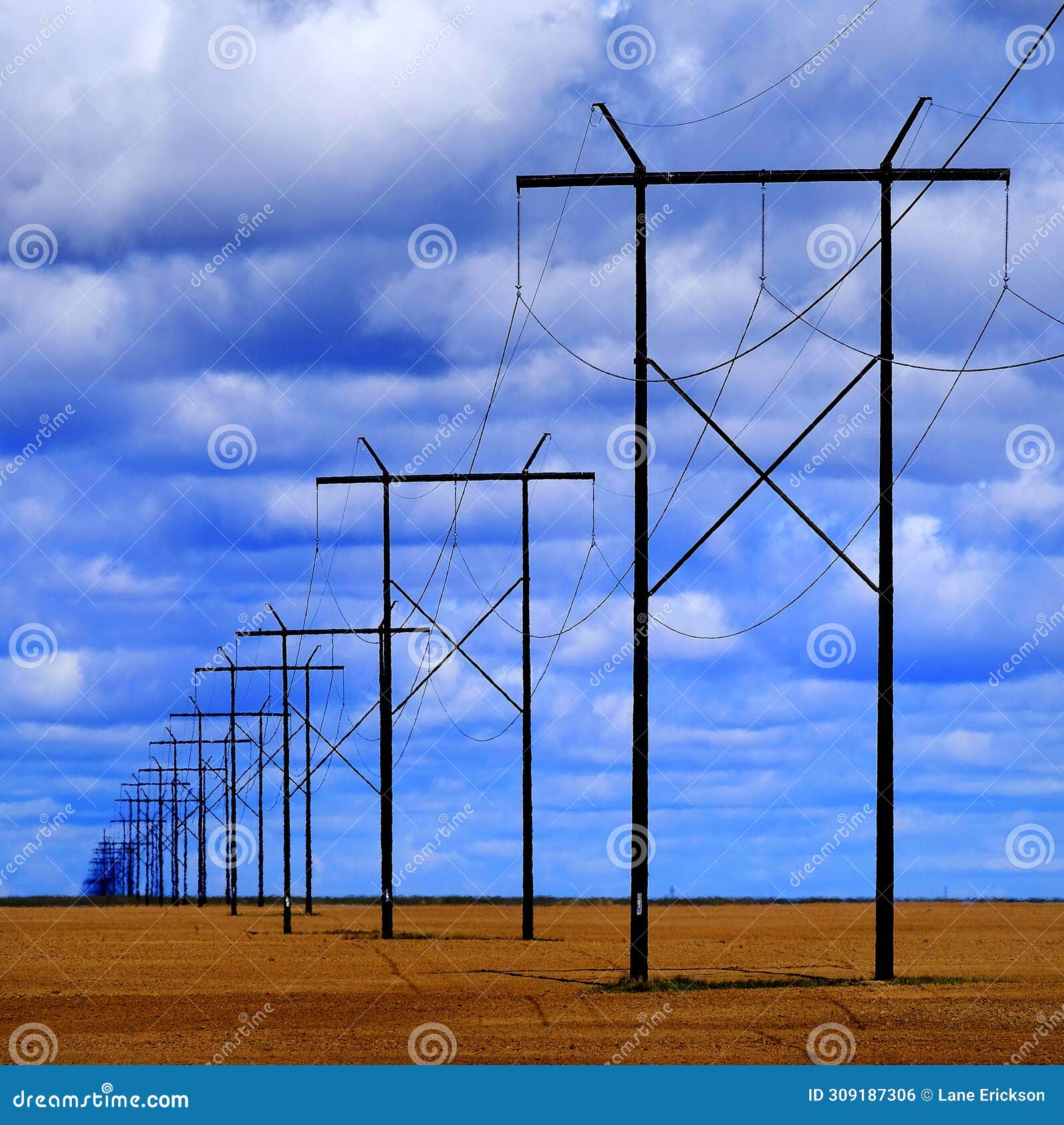 powerlines in field with blue sky and clouds