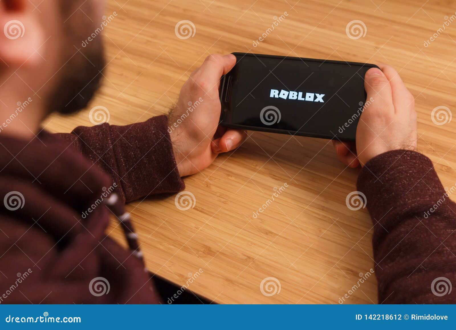 PRAGUE, REPÚBLICA CHECA - 16 de março de 2019: Homem segurando um  smartphone e jogando o jogo móvel Roblox. Imagem editorial ilustrativa  sobre fundo de bambu . — Fotografia de Stock Editorial ©