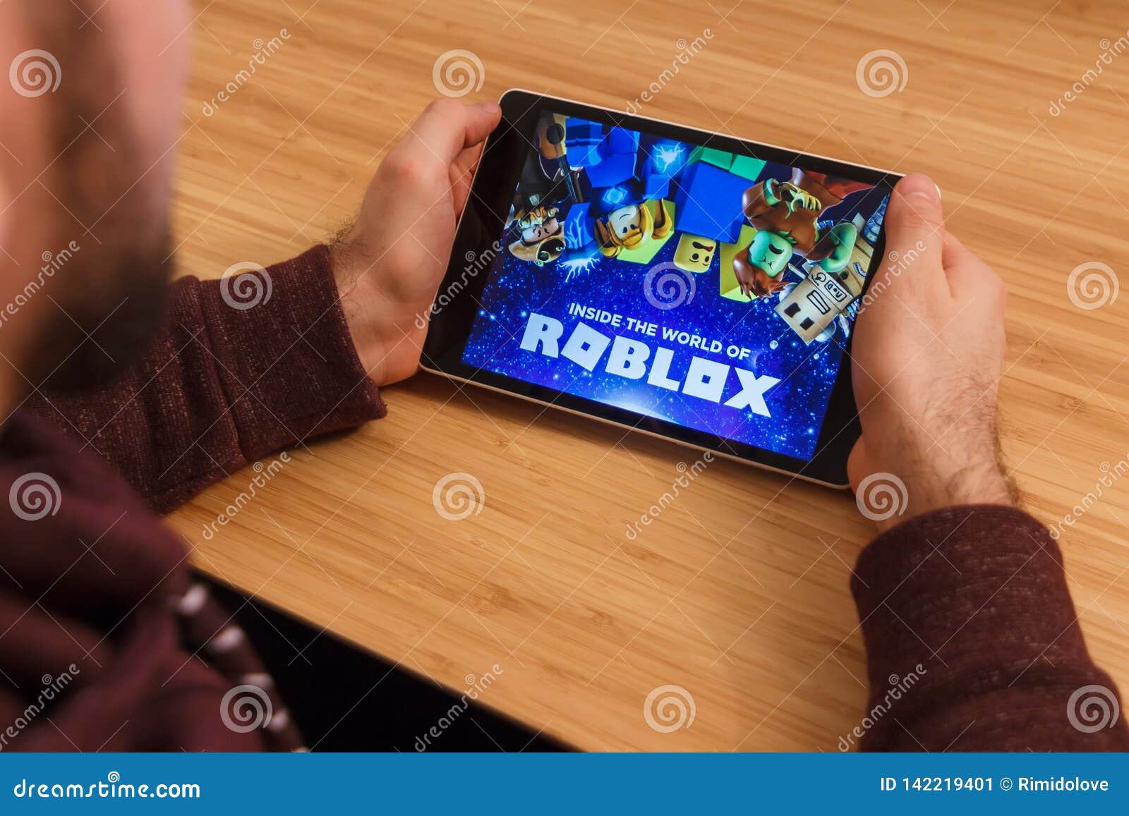 Prague Czech Republic March 16 2019 Man Holding A Smartphone - prague czech republic march 16 2019 man holding a smartphone and playng the roblox mobile game an illustrative editorial image on an bamboo background