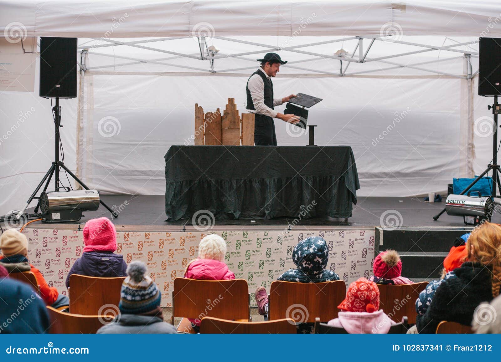 Prague December 18, 2016: Planlägg marknaden i Prague - man i hatt och passa showdockateatern på gataetapp framme. Planlägg marknaden i Prague - man i hatt och passa showdockateatern på gataetapp framme av barn som sitter på stolar