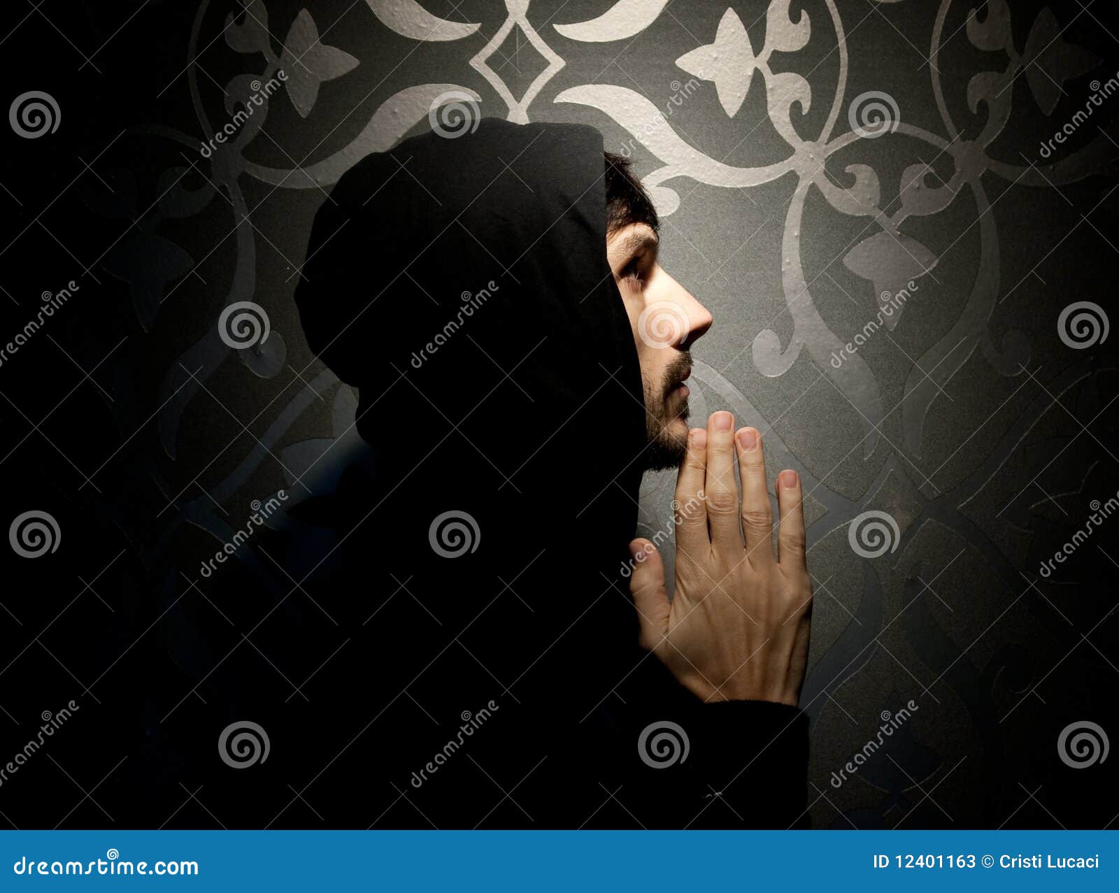 Young caucasian man with hood and beard praying