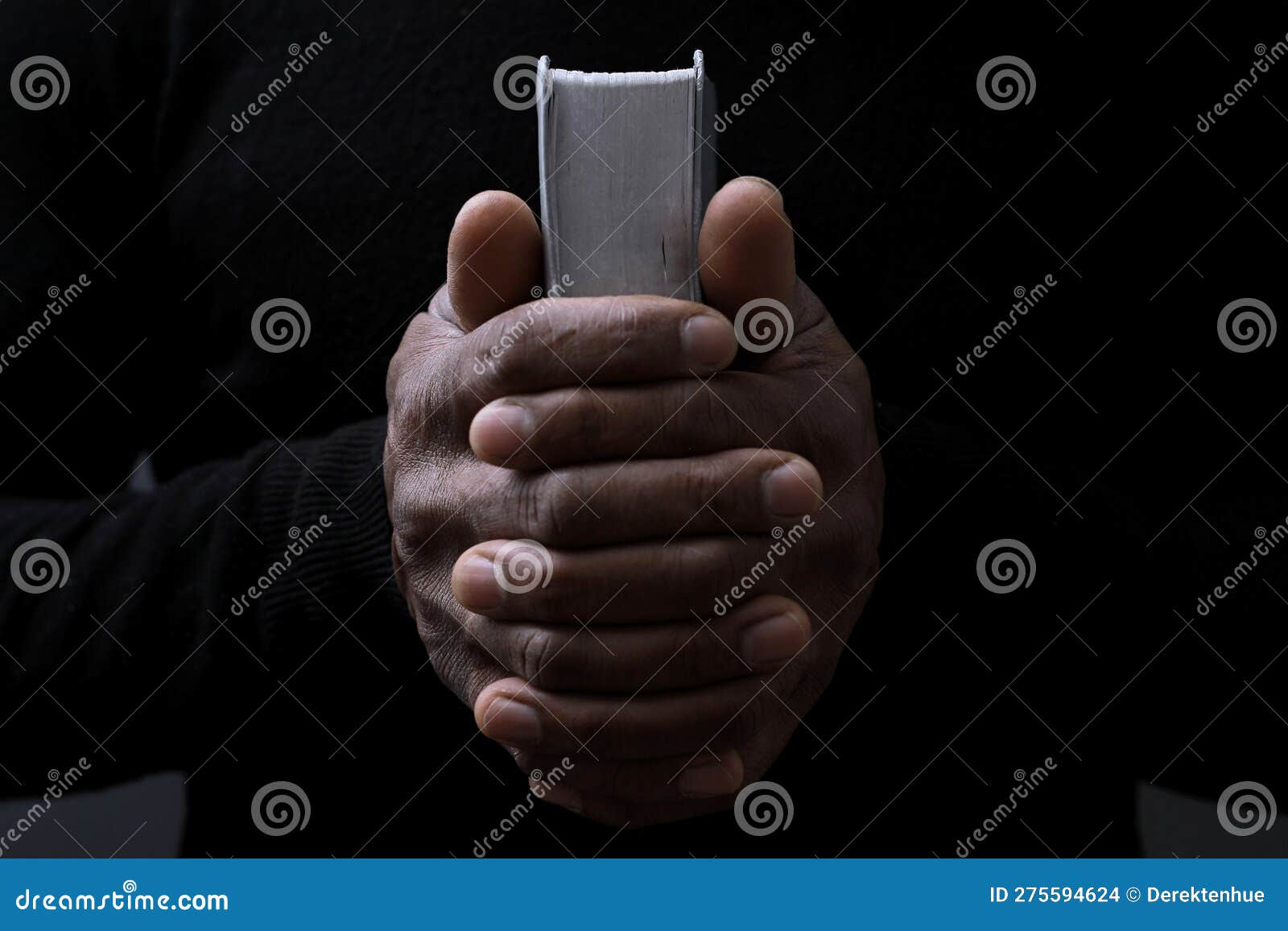 man praying to god with hands together on dark background stock photo