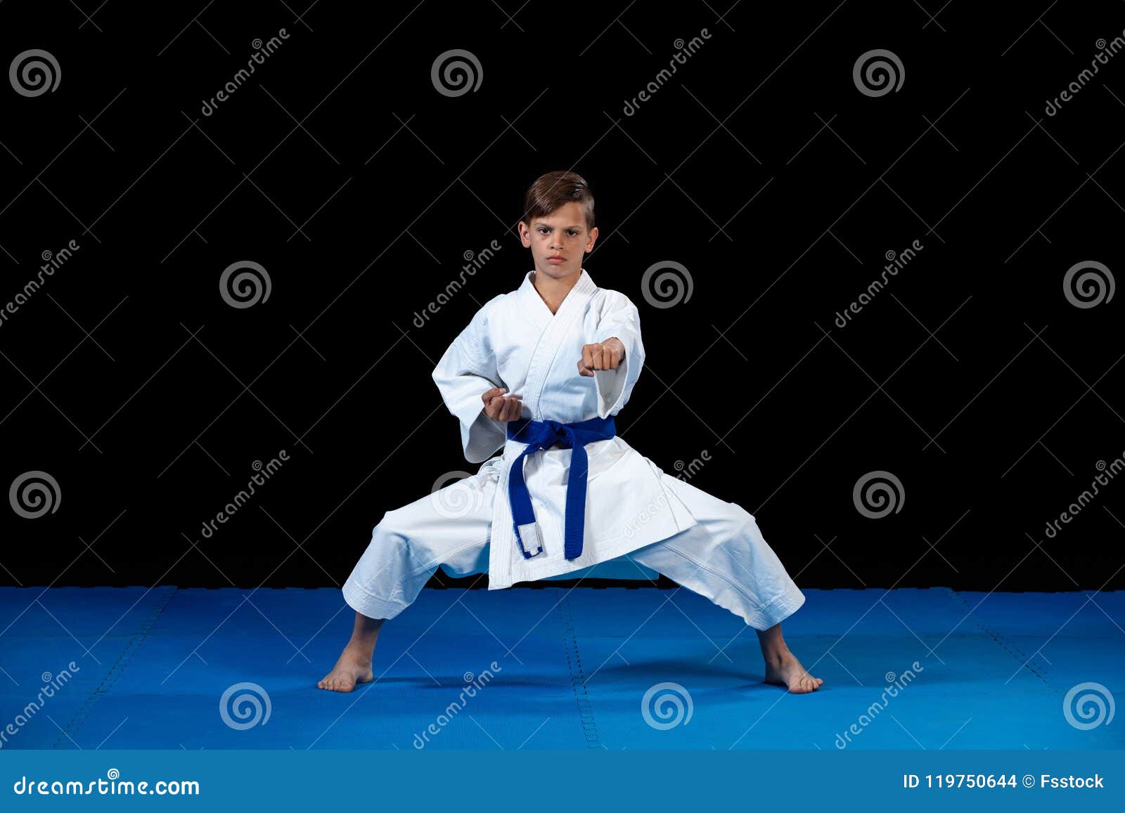pre-teen boy doing karate on a black background