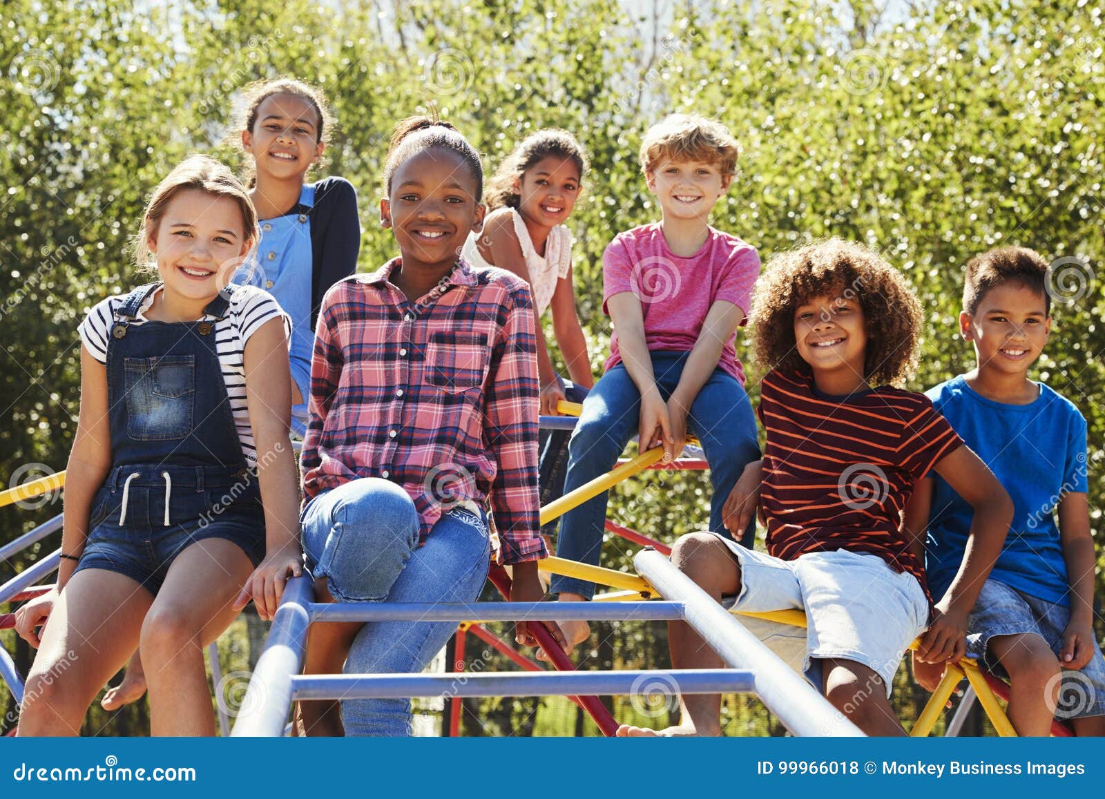 pre-teen friends sitting on climbing frame in playground