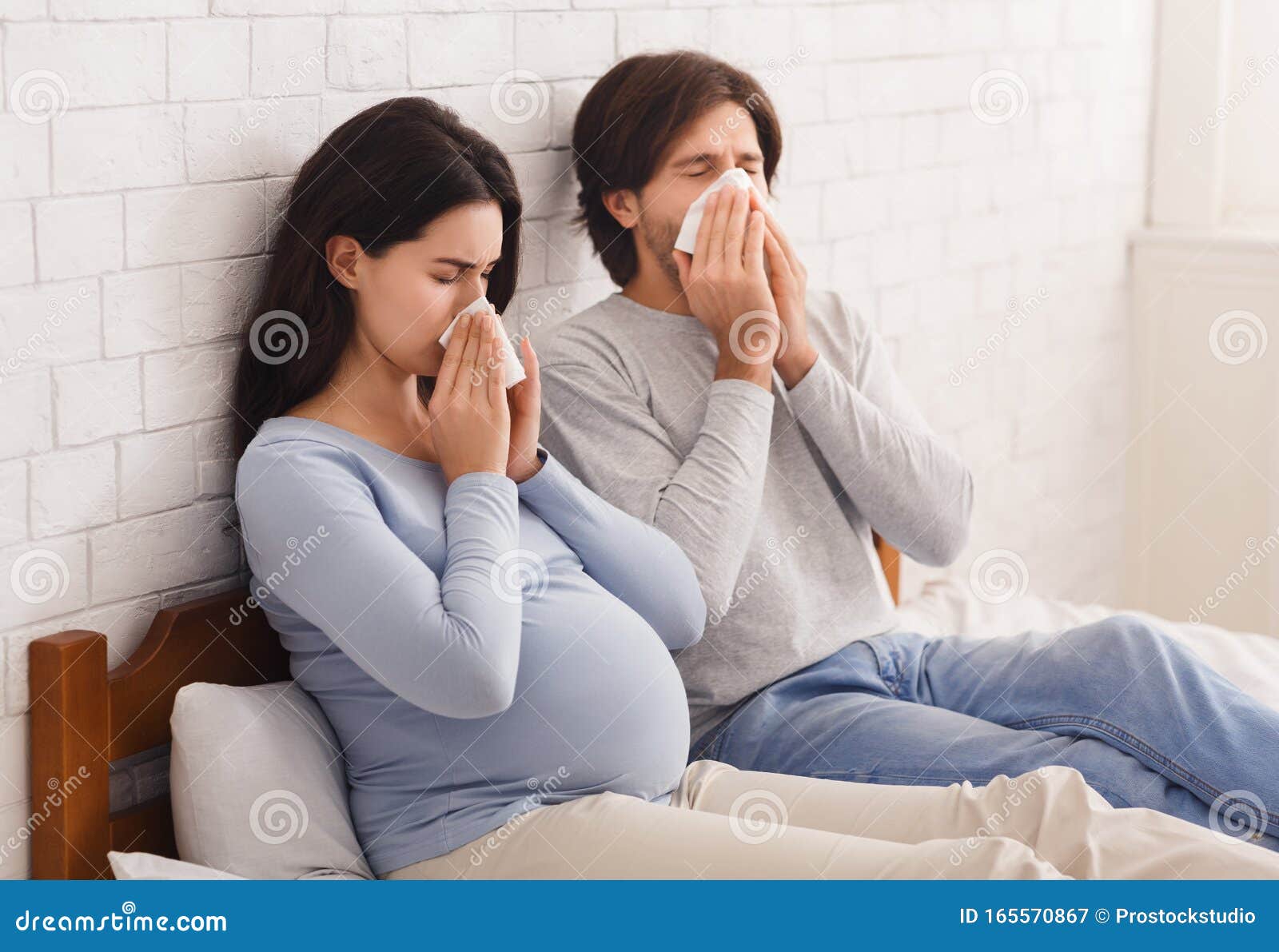 Pregnant Couple Feeling Sick, Sitting on Bed and Blowing Noses ...
