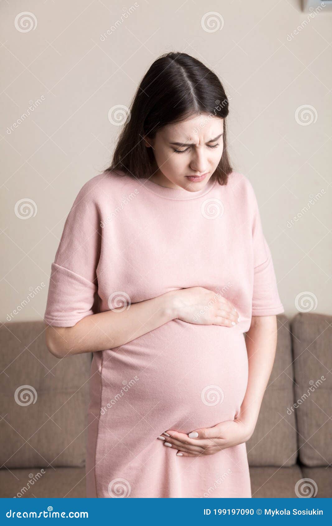 Pregnant Lady Having Massaging Lower Belly Sitting on Sofa Indoor
