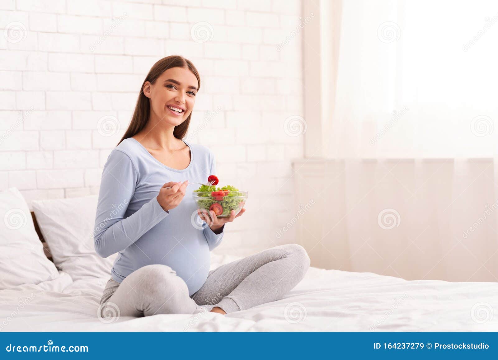 Pregnant Lady Holding Bowl with Salad Sitting in Bed Indoor Stock Image