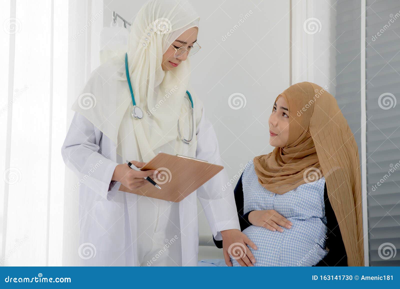 pregnant muslim woman with her muslim female doctor in clinic, gynaecology consultation