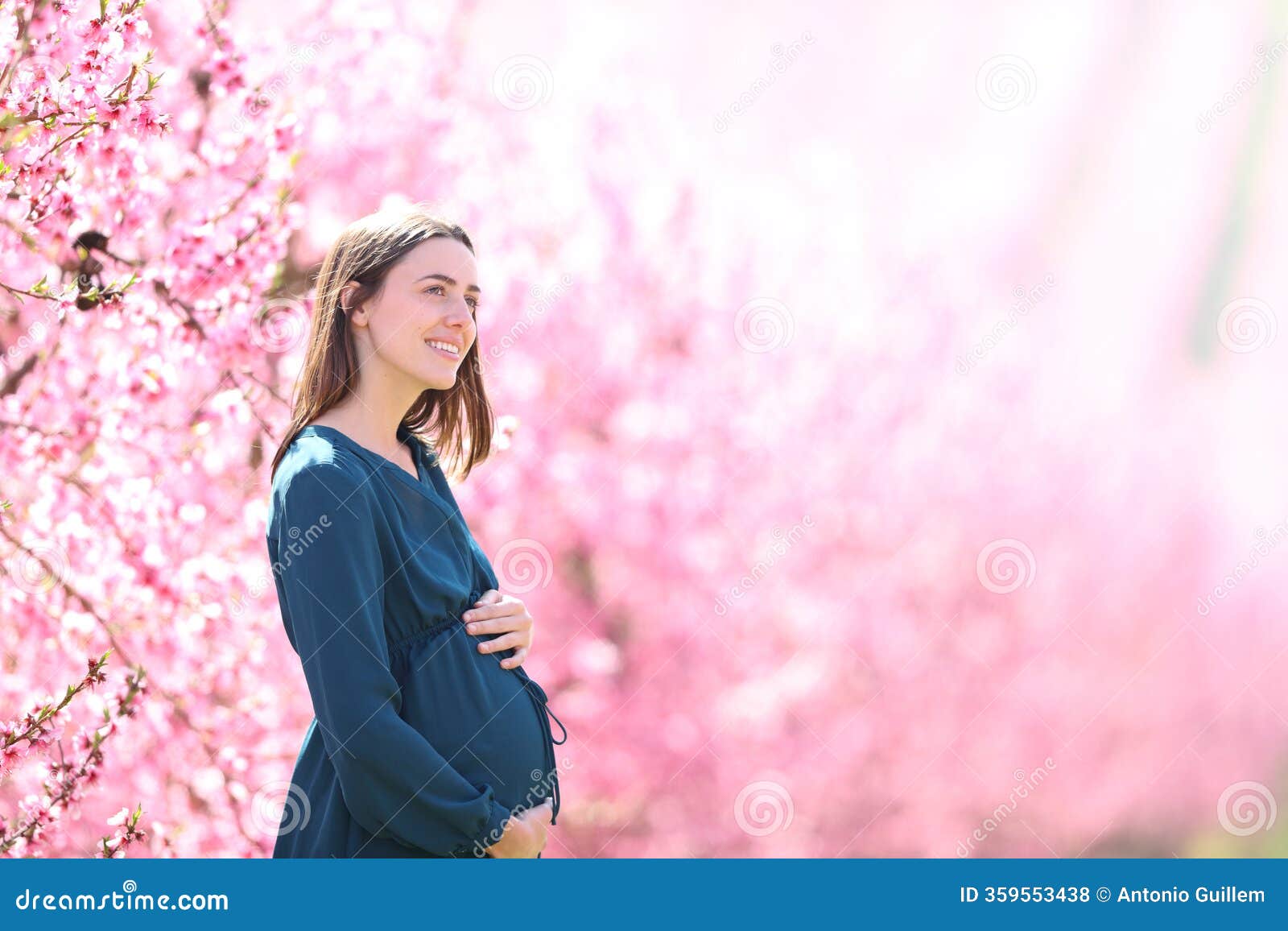 pregnant woman contemplating flowered field in nature