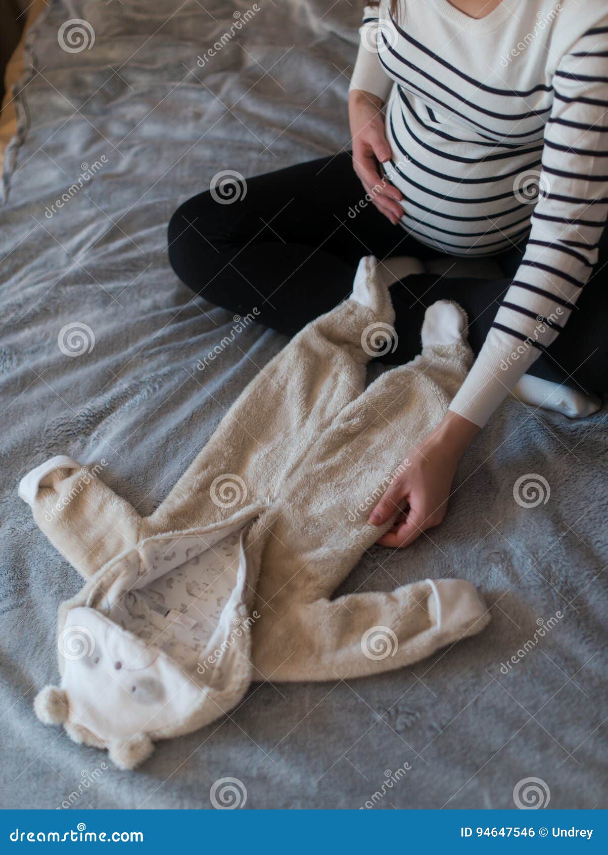Pregnant Woman Dreaming and Holding Baby`s Clothes Stock Photo - Image