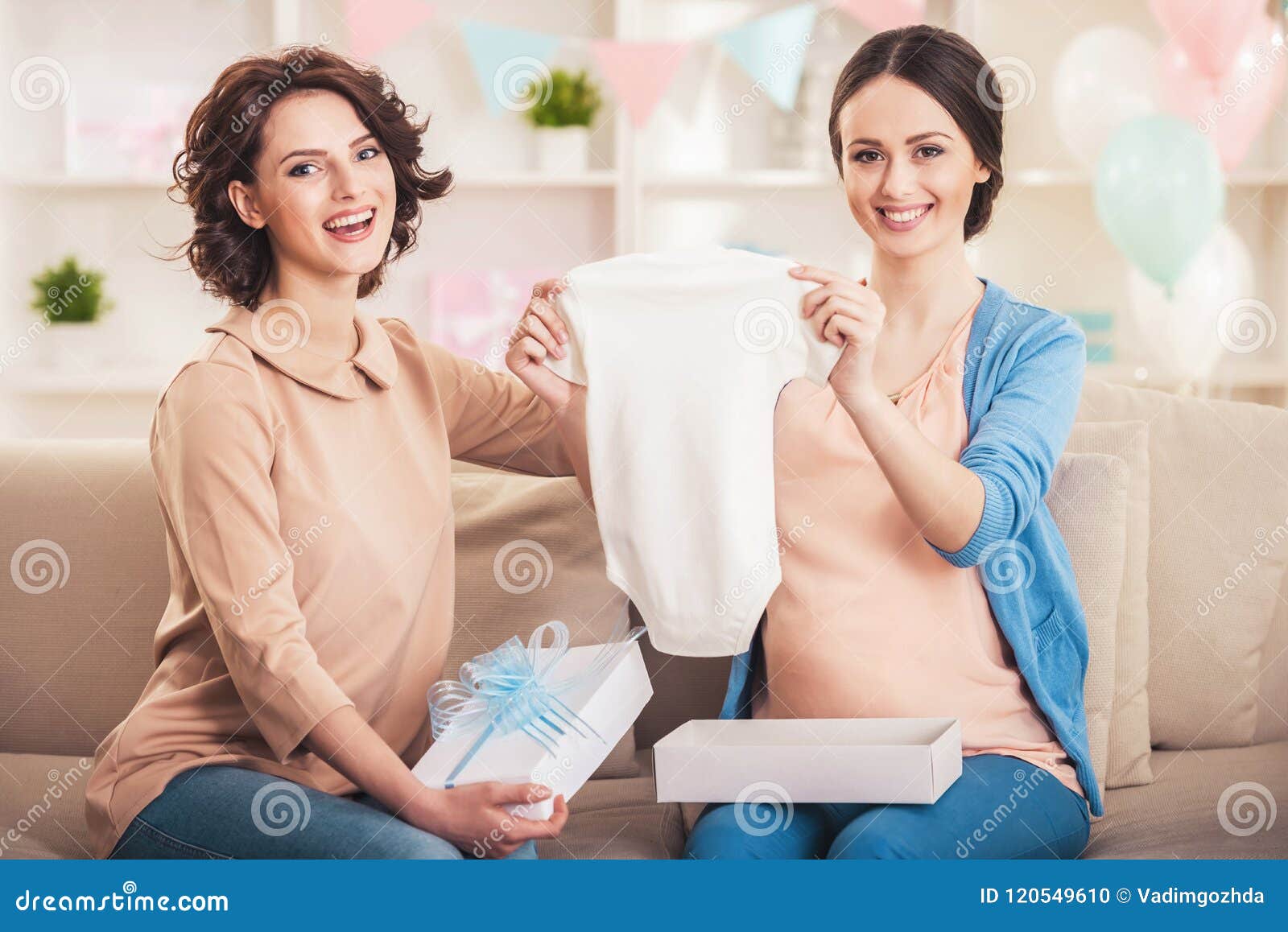 pregnant woman with friend holding baby romper.