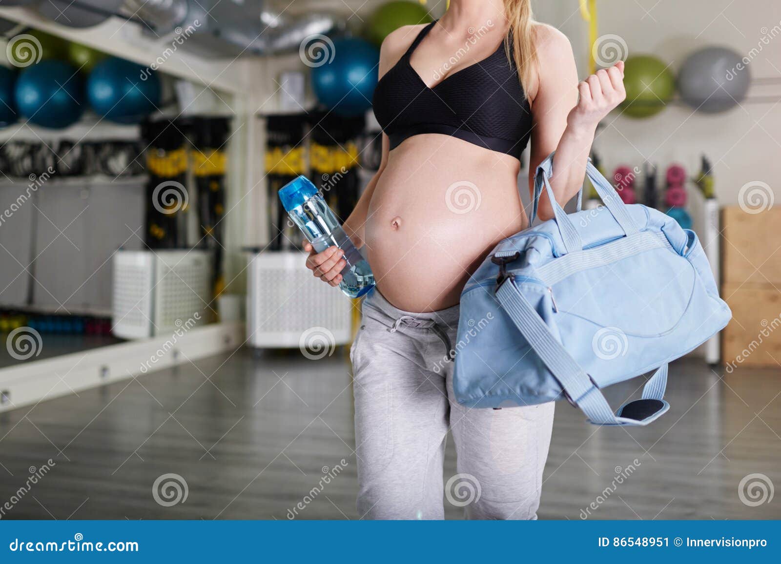 pregnant woman at the gym holding sport bag and bidon