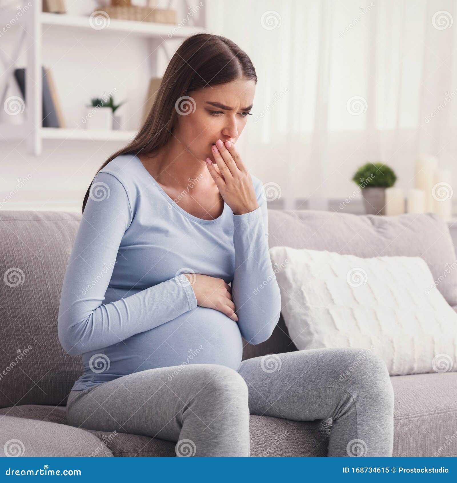 Pregnant Woman Having Pregnancy Morning Sickness Sitting On Couch Stock
