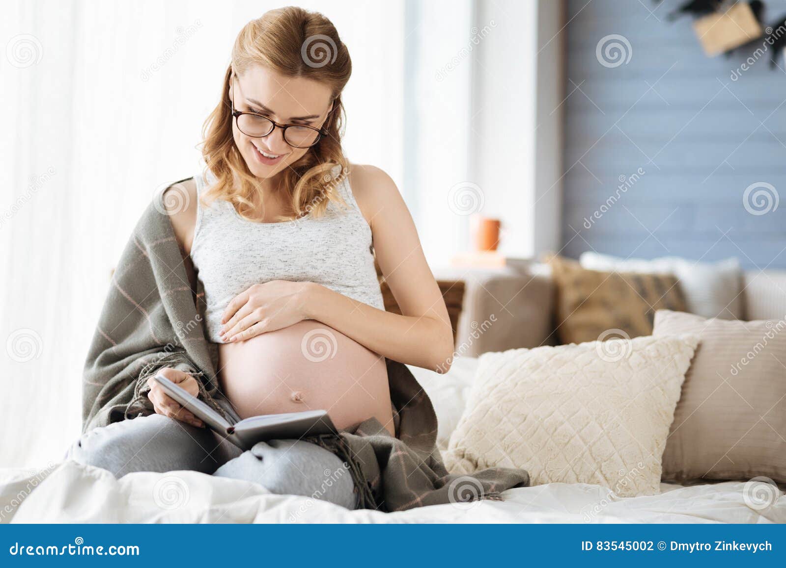 Pregnant Woman Relaxing With Book In Bedroom Stock Photo