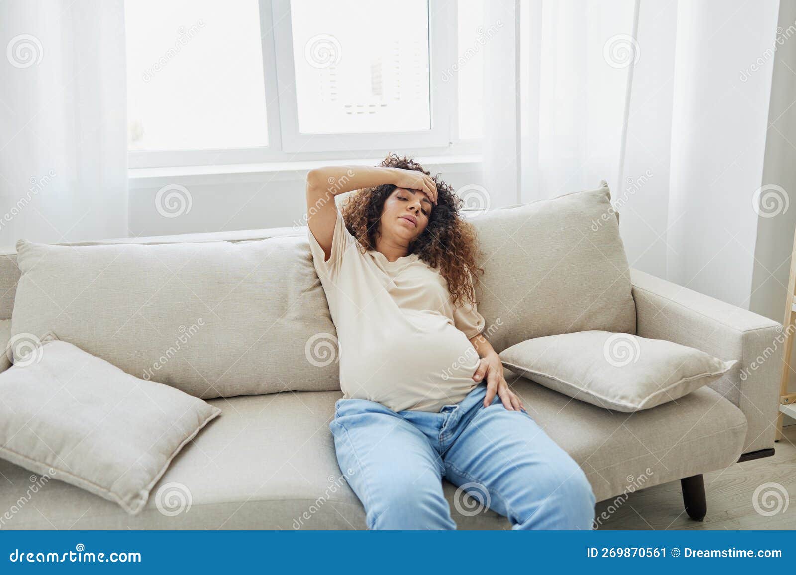 Pregnant Woman Sitting on the Couch at Home Headache, Pregnancy and ...