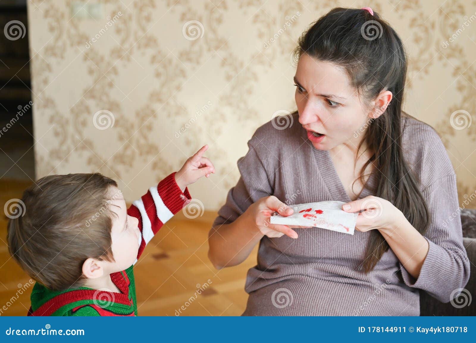 pregnant young woman scared with nosebleed. a little boy looks at his pregnant mom. healthcare and medical concept