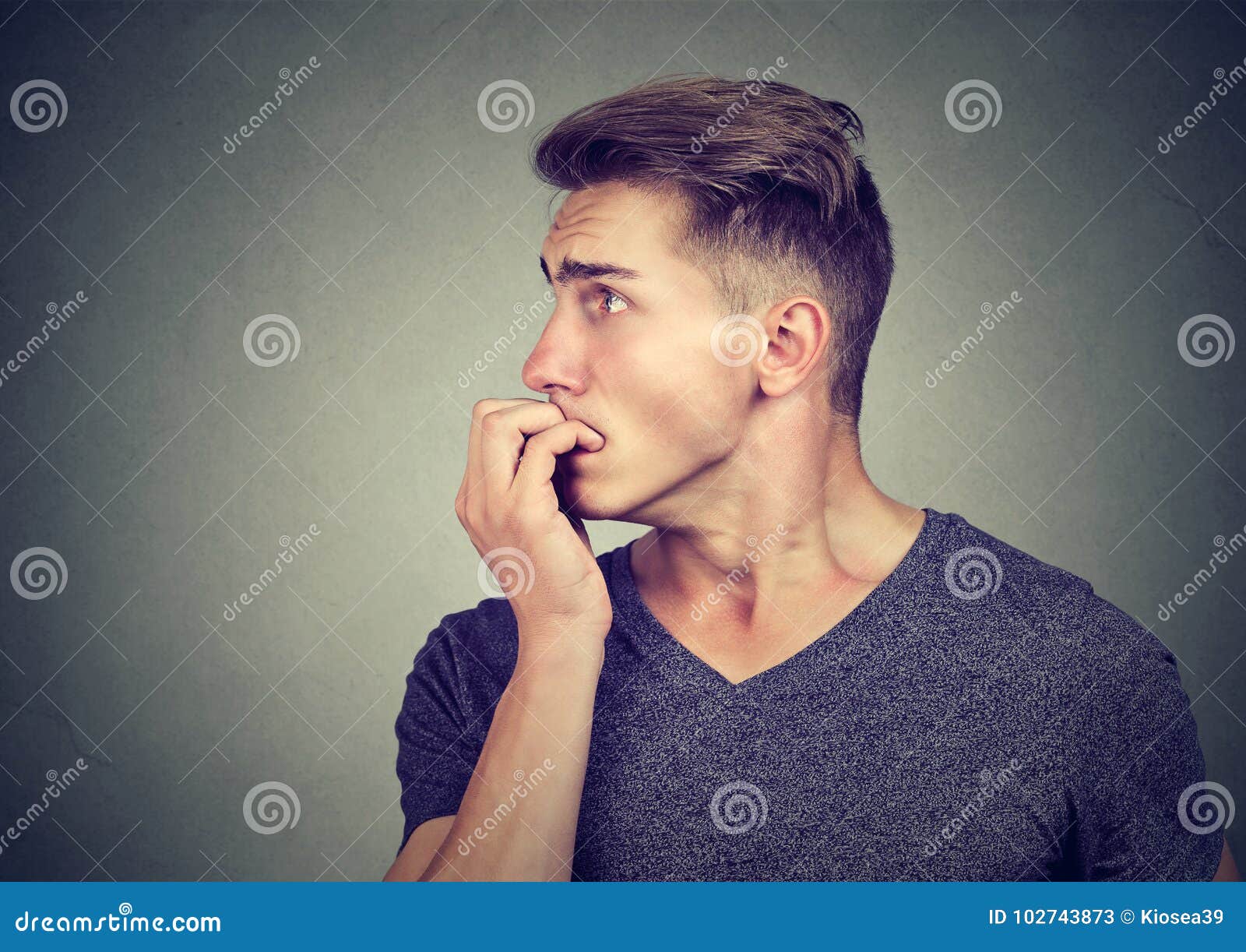 Preoccupied Anxious Young Man Biting His Fingernails Looking To the