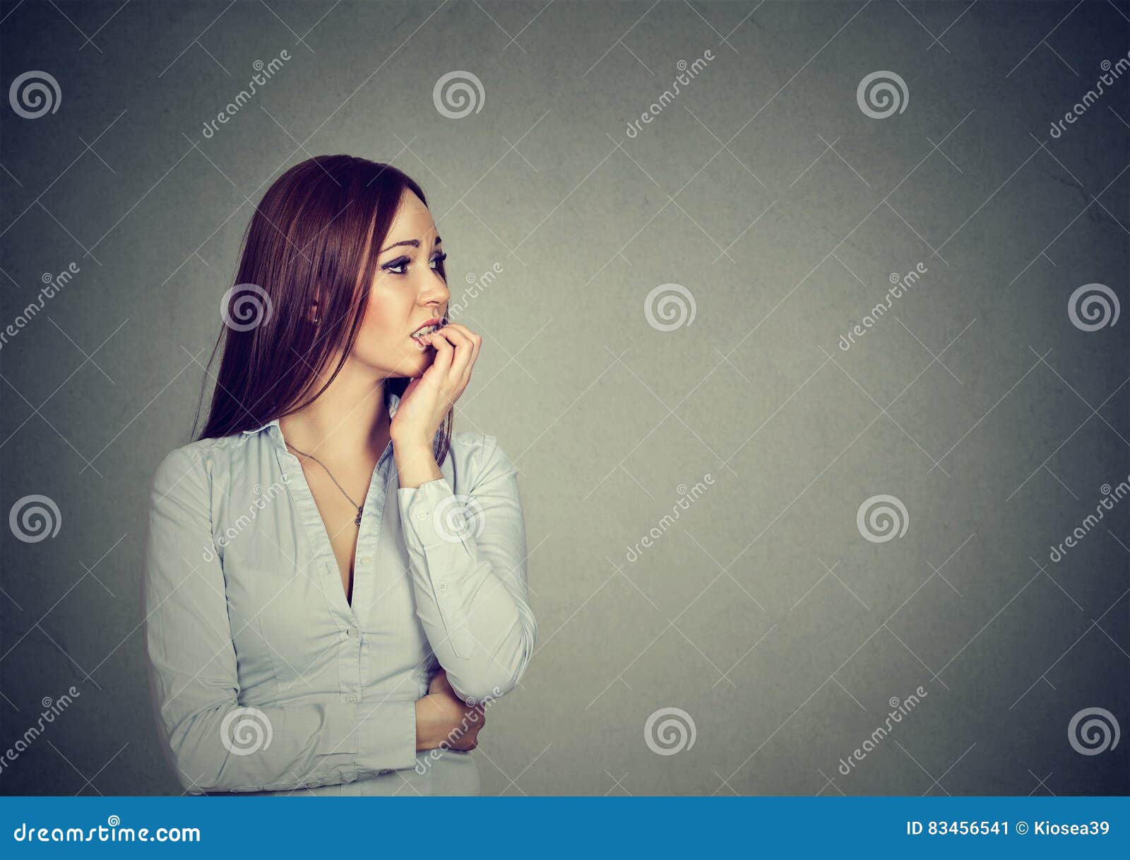 preoccupied anxious young woman biting fingernails
