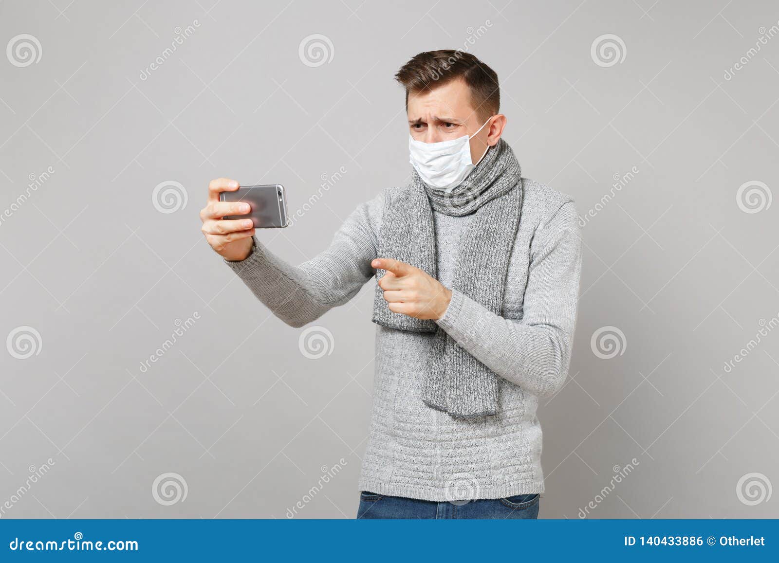 Preoccupied Young Man in Sweater, Scarf Sterile Face Mask Making Video Call  with Mobile Phone Pointing Index Finger Stock Photo - Image of clean,  people: 140433886