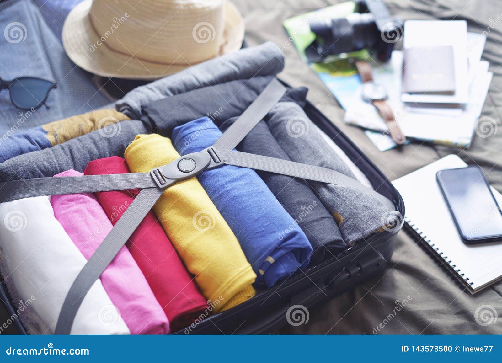 prepare accessories for new journey and travel to long weekend trip, packing clothes in suitcase bag on bed