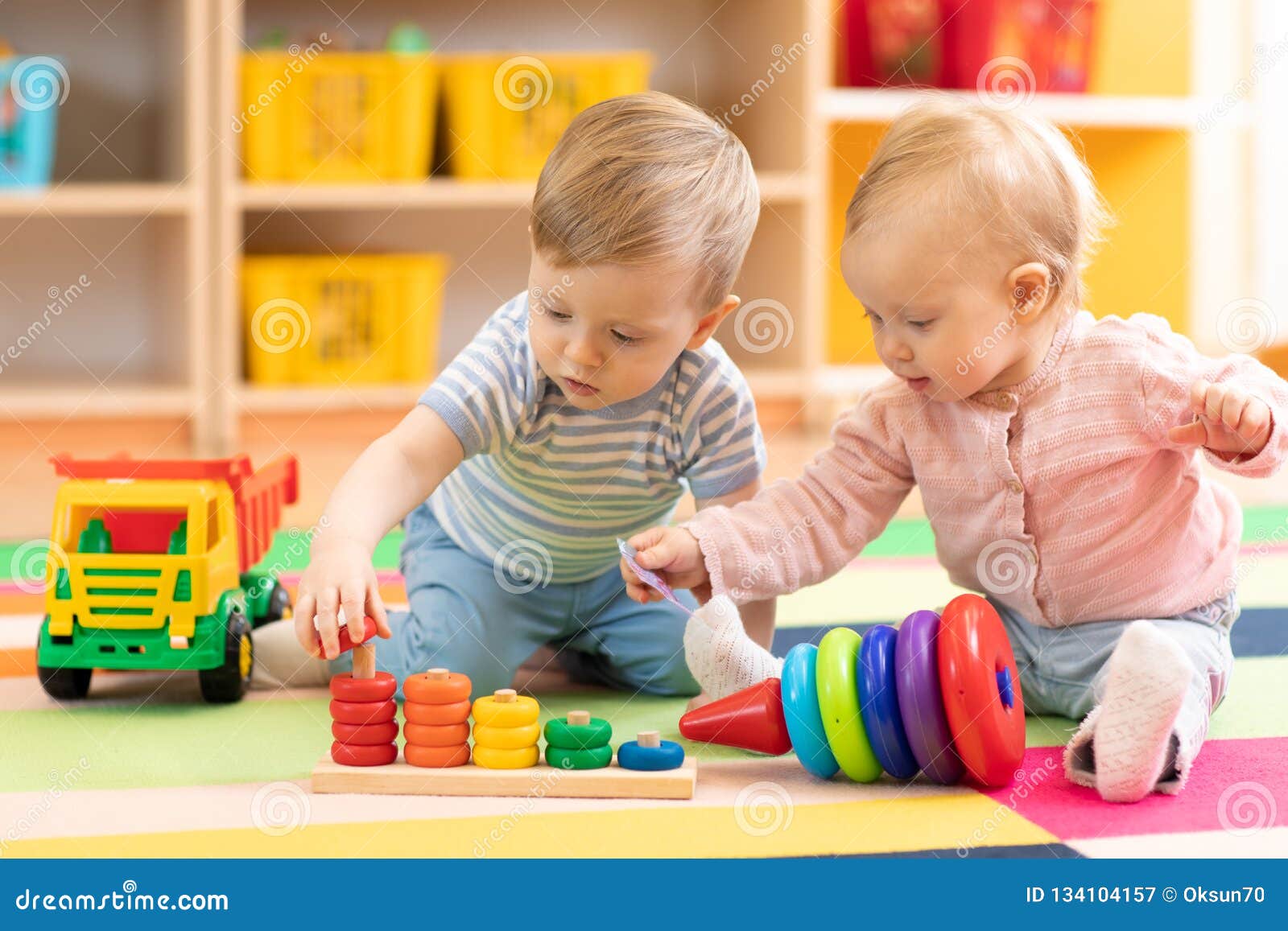 preschool boy and girl playing on floor with educational toys. children at home or daycare.
