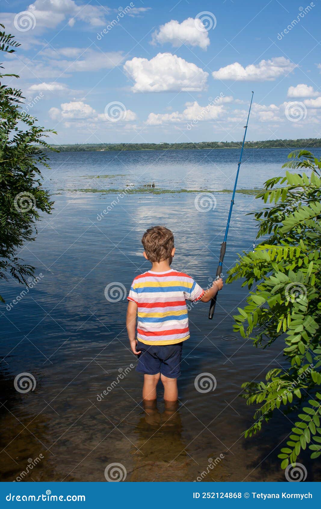Child is Fishing in River on Sunny Summer Day. Boy Casts a Fishing