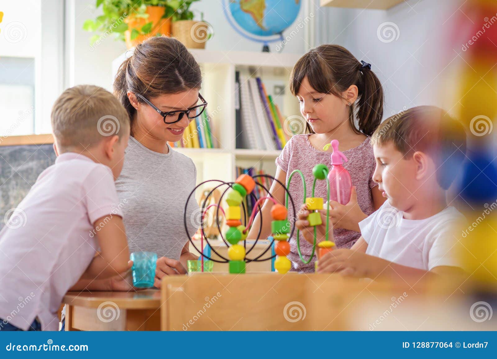 Preschool Teacher With Children Playing With Colorful Didactic Toys At
