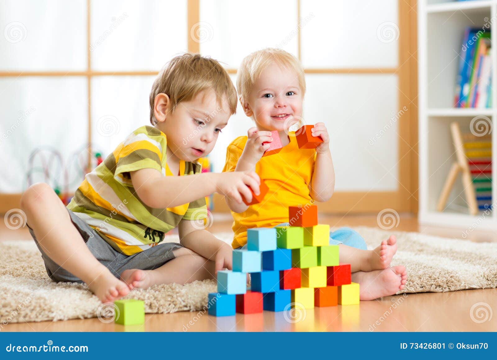 preschooler children playing with colorful toy blocks. kid playing with educational wooden toys at kindergarten or day care center