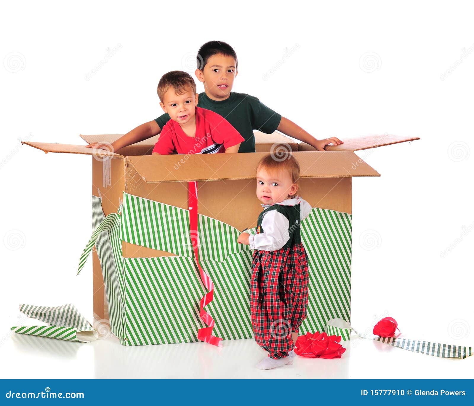 Presente de ?Funnest?. Três irmãos novos que jogam na caixa de um presente gigante do Natal. Isolado no branco.