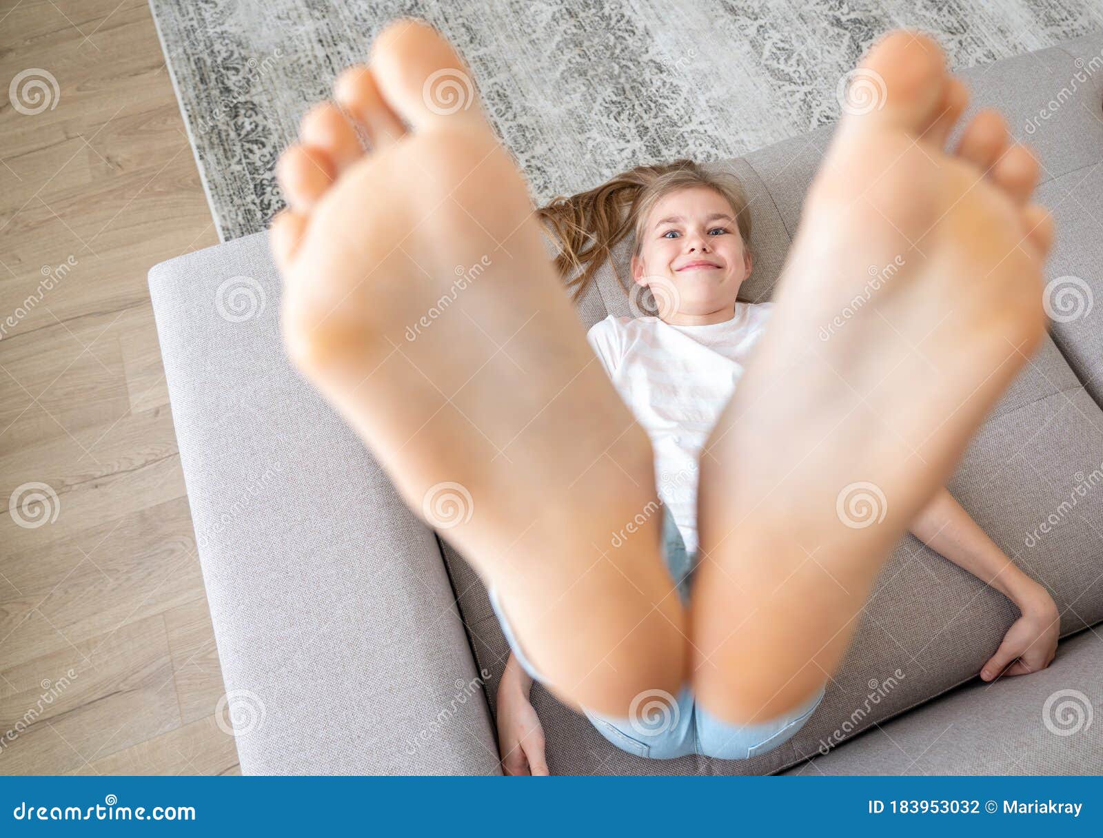 preteen girl lying on couch with her bare feet raising up high