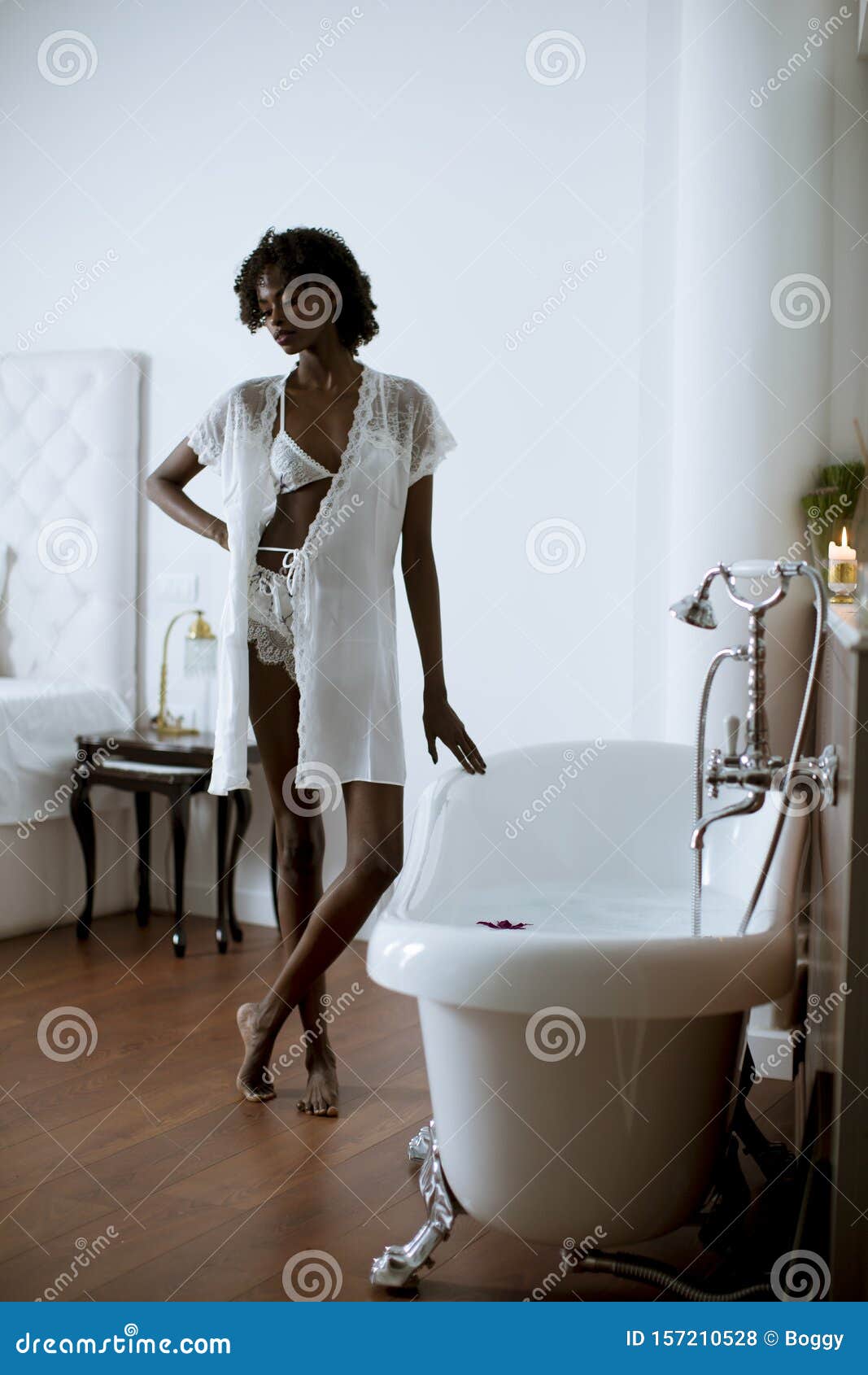 Pretty African American Woman Standing By The Bathtub In The Bathroom
